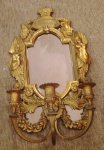 Aplique em bronze com três braços com espelho, decorado por figuras aladas e guirlandas.                                                             Encimado por coroa e cabeças em perfil.  Medidas:  Alt. 45 cm.  Larg. 26 cm.
