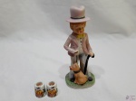 Lote composto de 2 pequenos castiçais em porcelana alemã e enfeite de menino com trajes típicos em porcelana. Medindo o menino 18cm de altura.