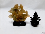 Lote composto de 2 enfeites, sendo um enfeite floral em resina e Buda sentado em madeira. Medindo o floral 15,5cm de altura.