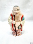 Escultura de Buda em porcelana com policromia. Medindo 20,5cm de altura.