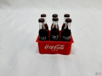 Miniatura de engradado com 6 garrafas da Coca-Cola. Medindo a garrafa 8cm de altura.
