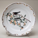 Prato decorativo, de porcelana SCHMIDT, pintado a mão, com motivos de pássaros, folhas e frutos (apresenta um pequeno defeito de fabrica na borda). Medidas aproximadas: 31 cm de diâmetro.
