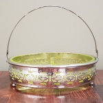 Petisqueira de metal espessurado a prata, com recipiente de cristal verde. Medidas aproximadas: 18 cm de diâmetro x 15 cm de altura.