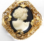 Broche em metal dourado, representado por camaféu. Medidas: 4,5 de comprimento X 4,5 de largura.