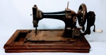 Antiga maquina de costura em ferro montada sobre base de madeira em bom estado de conservação . USA principio do século XX . mede 28 cm de altura x 50 cm de comprimento x 26 cm de largura .