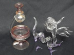 Duas peças em vidro de Murano transparente e roxo, representando Dragão. Alt. 15cm e mini decantador transparente e rosa, Alt. 16cm. Pé de um dos dragões quebrado.