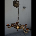 Lustre para 6 lâmpadas em metal dourado, decoração repuxada moldada em volutas e acantos na base, corpo e braços. Um braço quebrado, bocais no estado. 81 x 58cm.