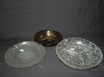 Três peças em vidro: a) Porta petisco redondo com 3 divisórias, translúcido, decoração geométrica. diam. 21cm. b) porta petisco fosco em forma de folha. Diam. 20cm. c) Bowl na cor âmbar decorado com girassól estilizado. Diam. 17cm.