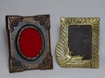 Dois porta-retratos em bronze: um moldado com pássaros e penas onduladas, aplicado com espelho na frente; e um levemente cobreado com acantos e flores moldadas nos cantos. 16 x 13cm.