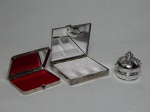 Três peças para maquiagens em metal prateado: 2 caixas porta-maquiagens com espelho e 1 recipiente de batom na forma de coroa. Maior 7 x 7cm.