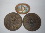 Três peças decorativas de parede: a) Dois medalhões em metal amarelo inglês, aplicados com cenas de tavernas em alto relevo. Diâm. 21cm. b) Placa em resina policromada representando menino pescando com cachorro. 13 x 18cm.