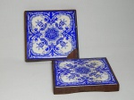 Dois suportes para pratos quentes em madeira, fundo com azulejos azul e branco. Azulejos com fios de cabelo e quebrados. 