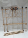 Cama de solteiro em ferro tubular patinado de bege, decorada com pinhas em metal dourado, bouquet de flores modelado e policromado aplicado no encosto da cabeceira e do pé. Estrado em 8 barras transversais de ferro. Marcas do tempo. Cabeceira 105 x 88cm. - -