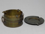 Dois cinzeiros em metal dourado, sendo um confeccionado na forma de capsula de bala de canhão, com alças. Marcas do tempo. 2 x 13cm e 7 x 12cm.