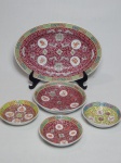 Conjunto de 5 peças em porcelana chinesa policromada aplicada com flores sobre fundo vermelho e caracteres chineses: 3 bowls pequenos, 1 bowl médio e 1 travessa. Maior 3 x 25 x 17cm, menor 3 x 10cm.