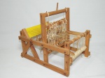 Miniatura de máquina de tear em madeira, aplicada com fios de lã. No estado. 30 x 35 x 26cm.