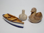 Três peças decorativas: a) Saboneteira na forma de pato e escultura de alho em pedra-sabão. Pato com a cabeça colada. 13 x 18 x 10cm e 9 x 7cm. b) Escultura de jangada em placa de madeira. 4 x 22 x 8cm.