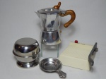 Quatro peças de cozinha diversas: a) Cafeteira dita italiana em inox, cabo e pega em madiera. Alt. 17cm. b) Mandolim para corte de frios em plástico e metal, regulável. 7 x 16 x 13cm. c) Açucareiro em aço inox Fracalanza liso. 10 x 10cm. d) Coador de chá em inox Hercules. Comp. 12cm.