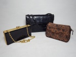 Três bolsas femininas: 1 em couro preto imitando pele de cobra; 1 em baquelite preto com guarnições em metal amarelo; e 1 em tecido jacquard marrom. 16 x 25 x 7cm, 10 x 20 x 4cm e 14 x 17 x 3cm.