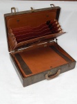 Antiga maleta em couro rígido, interior em couro marrom, mecanismo de tranca por senha numérica. Apresenta desgastes e marcas de uso. 34 x 46 x 12cm.