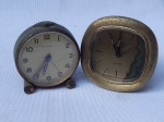 Dois relógios despertadores de mesa em metal amarelo: a) Marcado CYMA, mostrador com algarismos arábicos, manufatura suíça. 7 x 6 x 3cm. b) Marcado Bucherer, mostrador com marcadores  em barras, manufatura suíça. No estado. 8 x 7 x 2,5cm. Ambos apresentam desgastes e necessitam reparo.
