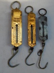 Três balanças "pocket balance" em metal para carnes e peixes, manufatura alemã. Pesos máximos 12, 20 e 25kg. Alts. 22, 21 e 25cm.