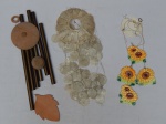 Três sinos dos ventos: 1 em porcelana na forma de girassol, 1 em material plástico e 1 em metal tubular. Necessitam reparos. Alts. 50, 51 e 67cm.