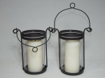 Par de lamparinas porta-velas em ferro fundido patinado com alça flexível, cúpulas em donzelas transparentes. Um com rachado. Vela de cera no interior. 19 x 18cm. - -