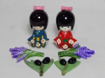 Conjunto de 6 peças em resina: duas bonecas gueixas em madeira laqueada, uma vermelha e a outra verde, 9 x 3cm; e quatro imãs de geladeira, par de feixes de trigo, 7 x 5cm, e um par de galhos de oliva, 7 x 5cm, um com as folhas quebradas.