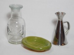 Três peças diversas: a) Antiga garrafa de farmácia em vidro translúcido, marcada no bojo com "Nº2". Alt. 18cm. b) Azeiteiro em aluminio, capacidade para 250ml, marca da Moulin Costelas, França.Alt. 15cm. c) Saboneteira em cerâmica vitrificada na cor verde. 4 x 15 x 12cm.