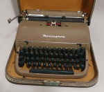Máquina de escrever da marca Remington, modelo Quiet Riter, com fixação na base da caixa. Carro movimentando. 
