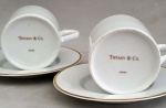 THIFANY & CO. Elegante dupla de xícaras Tiffany, de porcelana branca com friso dourado