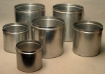 Seis latas de mantimentos em alumínio (sem as tampas). A maior possui 23 cm de altura e diâmetro de 22 cm