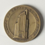 Medalha Banco do Estado de São Paulo comemorativa ao lançamento da primeira pedra do Edifício Sede do Banco de São Paulo, datada de 1939, sob a Presidência do Interventor Adhemar Pereira de Barros. Mede 05 cm de diâmetro.