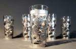 Conjunto com 05 copos para shot sobrepostos por prata de lei mexicana com motivos florais. México, séc. XX. Capacidade 20 ml, 08 cm de altura