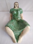 Escultura em cerâmica, representando mulher deitada, medindo 26cm de comprimento e 14cm de altura.