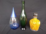Três garrafas diversas, sendo uma da marca Evion, de origem francesa, medindo 26cm de altura, outra em vidro na cor verde, medindo 34cm de altura, e outra em cerâmica mostarde, medindo 21cm de altura.