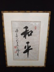 Gravura com caracteres japonês, com moldura em bambu, medindo 47x63cm.