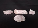 Quatro pedras brutas de quartzo rosa.