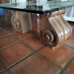 Mesa de centro com pés em madeira maciça estilo peanha e tampo de vidro 20mm. Apresenta um bicado no vidro . Mede: 90x120x48 cm.
