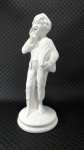 O JORNALEIRO - Grande escultura em faiança de tom branco representando garoto vendendo jornais, mede 43 cm de altura por 16 cm de diâmetro na base.