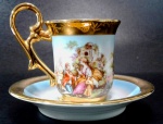 PORCELANA PÁTRIA - xícara para café com farta pintura em ouro decorada por flores e cena galante em rica policromia e detalhes. Mede 6 x 5,5 cm a xícara e 10,5 cm de diâmetro o pires.