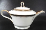 PORCELANA MAUÁ - Grande bule para chá manufaturado em porcelana branca com pintura em ouro na alça, bico, pega da tampa e faixas de arabescos. Mede 16 cm de altura por 27 cm da alça ao bico.