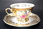 PORCELANA DP 541 - Elegante xícara colecionável para café em porcelana com pintura em ouro e decoração de cena galante na xícara e no pires. Mede 5 x 6,5 cm a xícara e 11 cm de diâmetro o pires.