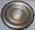 ANTIGO PRESENTOIR CONFECCIONADO EM METAL ESPESURADO A PRATA, BORDAS CINZELADAS COM DECORAÇÃO FLORAL EM SUA GALERIA CENTRAL. PERDAS NO BANHO. MEDINDO 43,5 CM DE DIÂMETRO