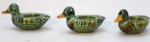 conjunto de 3 esculturas retratando patos confeccionadas em porcelana vitrificada na cor verde. medindo 5 x 6 x 11,5 cm