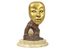 DORINHA DUVAL - Escultura representando máscara, em Bronze polido, bronze bruto pintado em marrou, com ovo em cristal ao centro, base em mármore claro duplo.Dimensões: 32,5 cm X 18 cm X 8 cm (Alt./Comp./ Larg.); Base: 27 diâm. Assinada no canto esquerdo da parte traseira. NÃO PODE SER DESPACHADA PELOS CORREIOS.