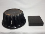 Duas bases: a) Mármore negro, 15 x 15 x 4cm. b) Porcelana preta, formato ondular. 13 x 27cm. No estado e com marcas do tempo.