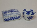 Duas peças em porcelana azul e branca: a) Caixa porta-joias, decoração de folhagens, tampa com decoração de vila sob montanhas. 6 x 13 x 10cm. b) Tigela, borda recortada, decoração de dragão chinês em azul borrão. 6 x 11cm.