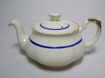 Chaleira em porcelana britânica na cor creme, aplicado com frisos azuis e detalhes em douração. Desgastes na douração. Marcada Grindley, Inglaterra, cerca 1936. 14 x 22 x 14cm.